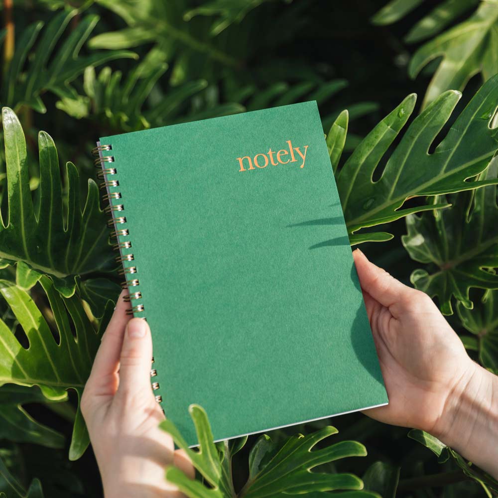 Forest Green &amp; Copper Notebook in hand against leaves