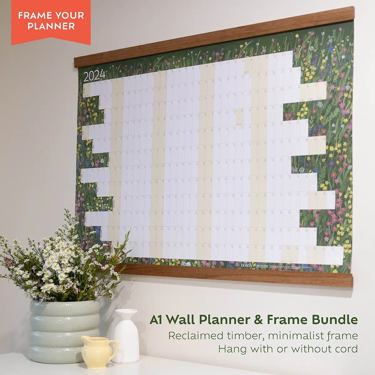 Notely A1 wall planner on side view with timber frame and flowers in pot